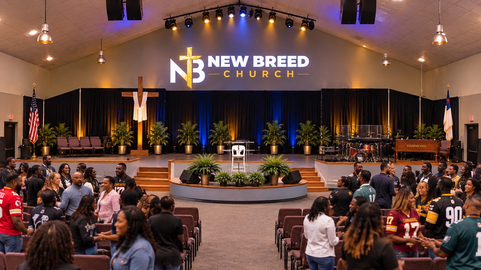 New Breed Church members greeting one another in the sanctuary, with the cross and stage in view